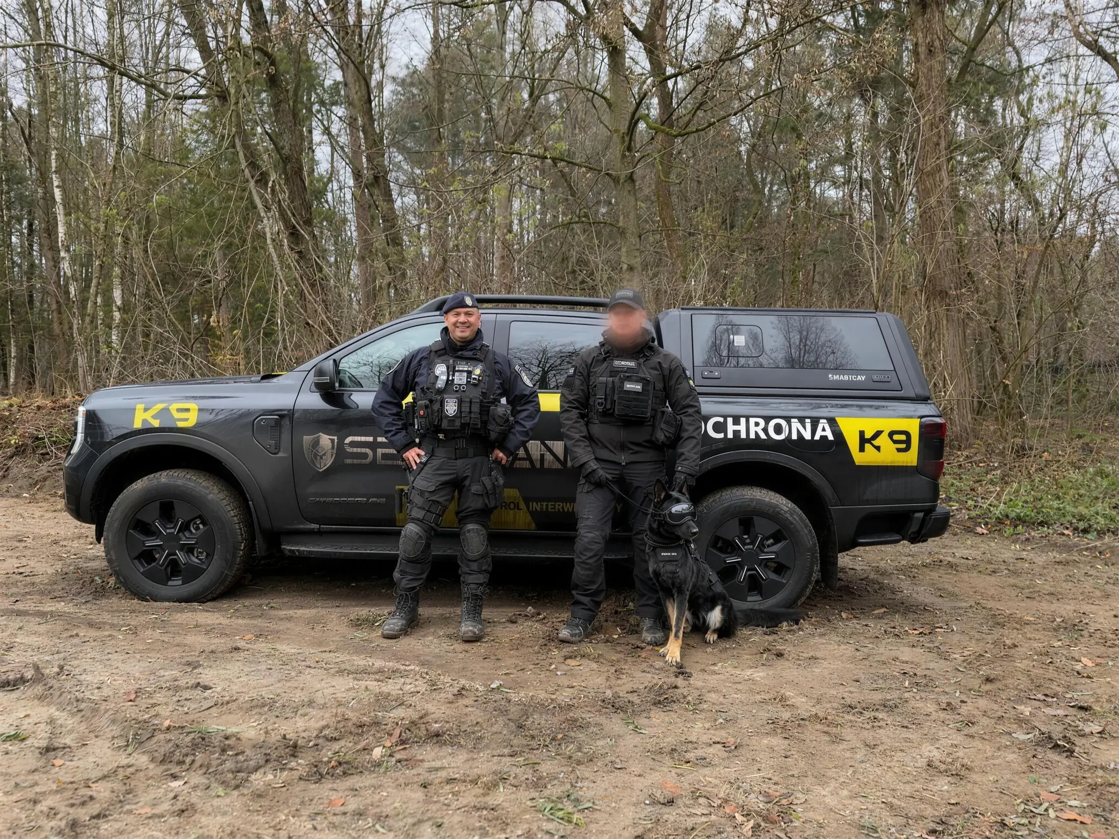Przewodnicy Securand z psem służbowym przy oznakowanym pojeździe patrolu K9 w terenie